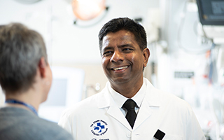 Emergency physician and scientist Dr. Venkatesh Thiruganasambandamoorthy smiles at a patient.
